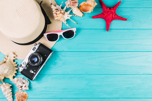 Cámara y sombrero cerca de gafas de sol y conchas marinas