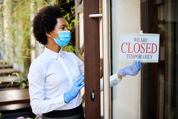 Foto gratuita camarera afroamericana cerrando un café debido a la pandemia de coronavirus