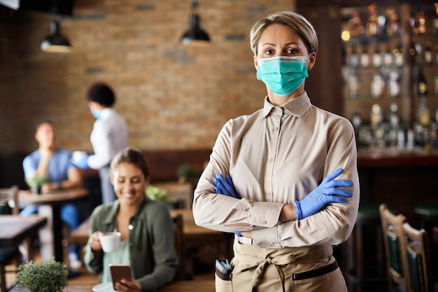 Camarera confiada con mascarilla protectora y guantes mientras trabaja en un café