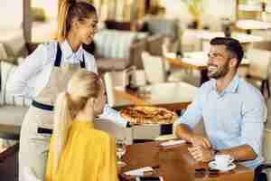 Foto gratuita camarera feliz sirviendo pizza a una pareja en un restaurante