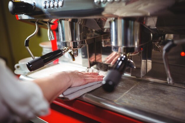 Camarera limpiar la máquina de café espresso con la servilleta en la cafetería ©