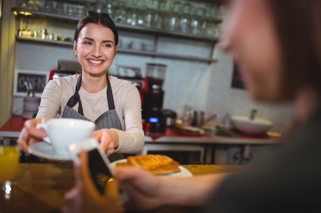 Foto gratuita camarera que sirve una taza de café para el cliente