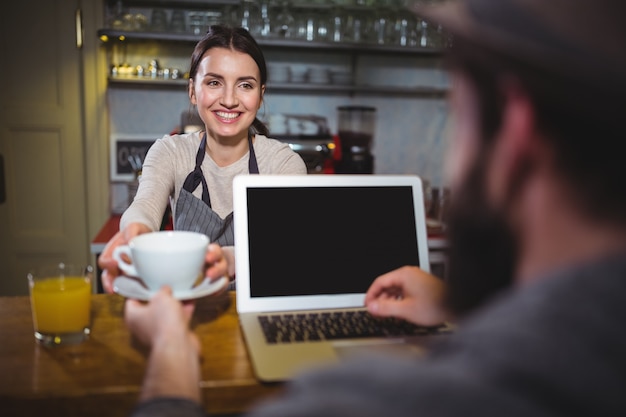 Camarera que sirve una taza de café para el cliente