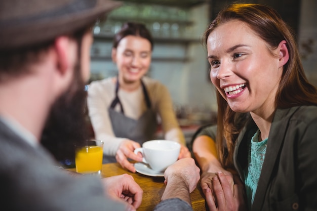 Camarera que sirve una taza de café a los clientes