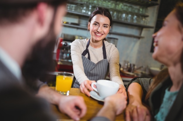 Camarera que sirve una taza de café a los clientes