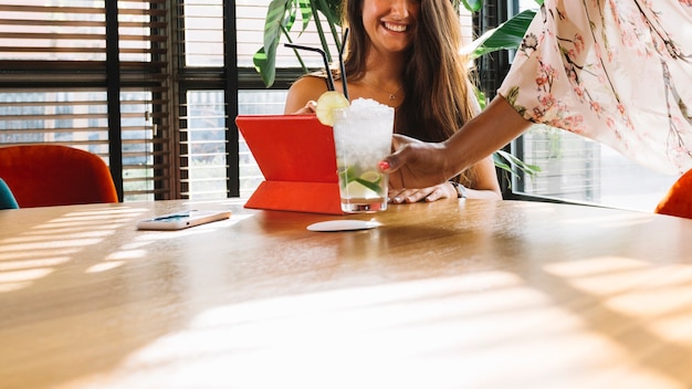 Foto gratuita camarera de sexo femenino que sirve el coctel al cliente femenino en la tabla de madera