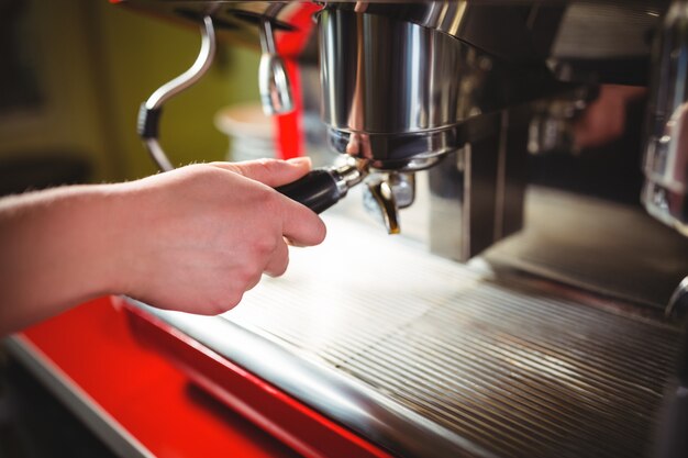 Camarera usa la máquina de café espresso en el mostrador