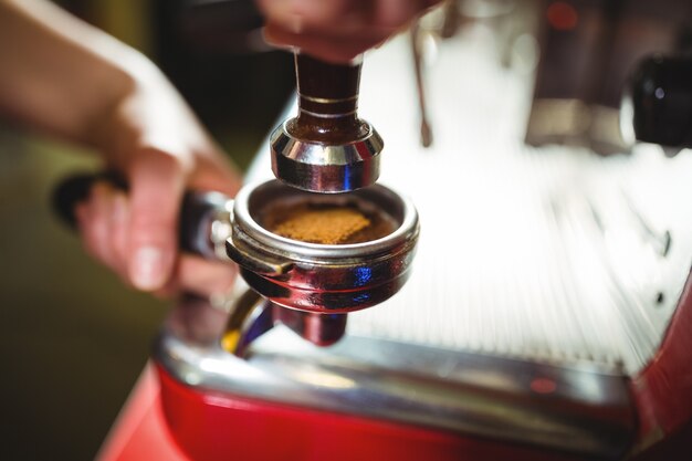 Camarera utilizando un pisón para presionar café molido en un portafiltro