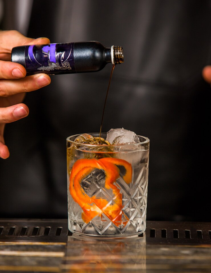 Foto gratuito camarero agregando bebidas alcohólicas en un vaso con coco, naranja pelada y cubitos de hielo