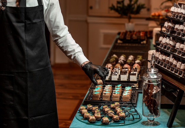 Camarero ajusta una mesa de banquete con dulces