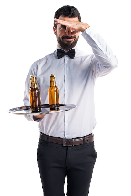 Camarero con botellas de cerveza en la bandeja haciendo oliendo mal gesto