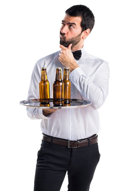 Camarero con botellas de cerveza en la bandeja de pensamiento