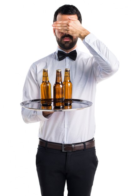 Camarero con botellas de cerveza en la bandeja que cubre sus ojos