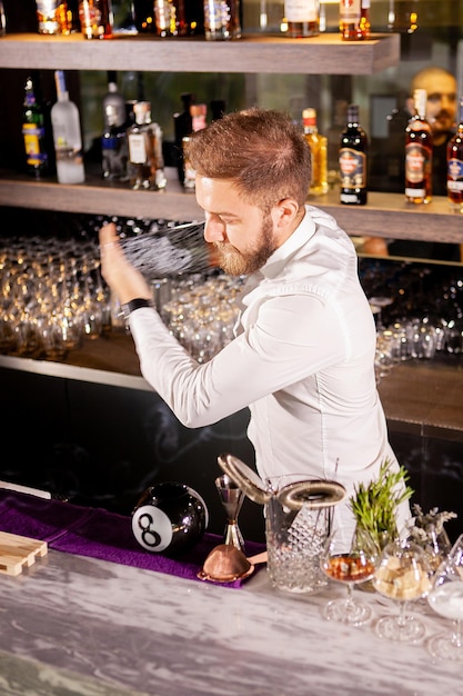 El camarero está haciendo cócteles en la barra del bar en el salón