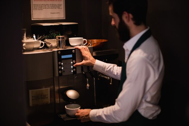 Camarero haciendo una taza de café de la máquina de café espresso