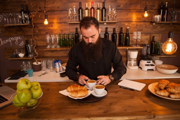 Camarero hipste con cuentas preparando café detrás de la barra del bar