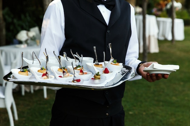 Camarero lleva placa con deliciosos aperitivos