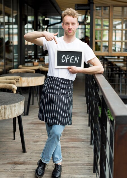 Camarero masculino con delantal con cartel abierto