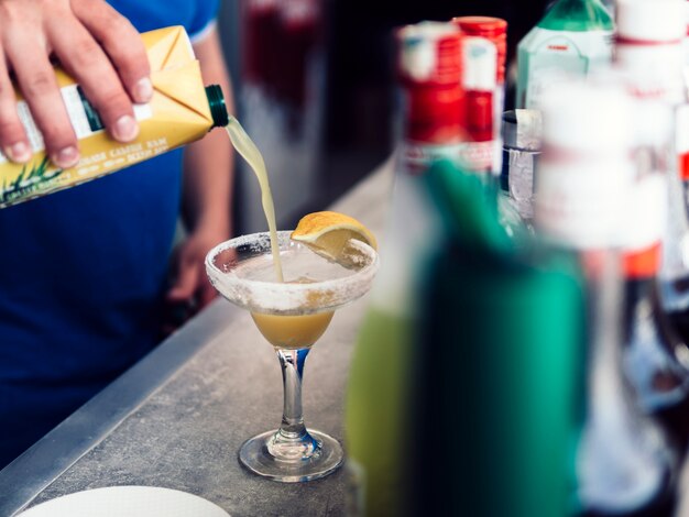 Camarero masculino haciendo bebida colorida con jugo