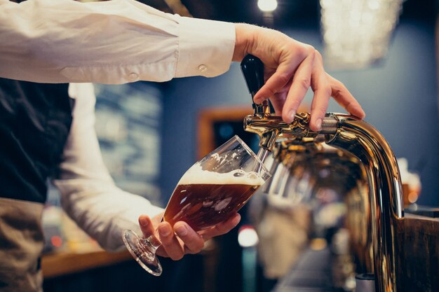 Camarero masculino vertiendo cerveza en un pub