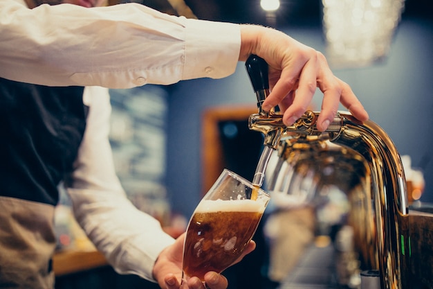 Camarero masculino vertiendo cerveza en un pub