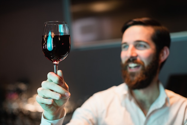 Foto gratuita camarero mirando una copa de vino tinto