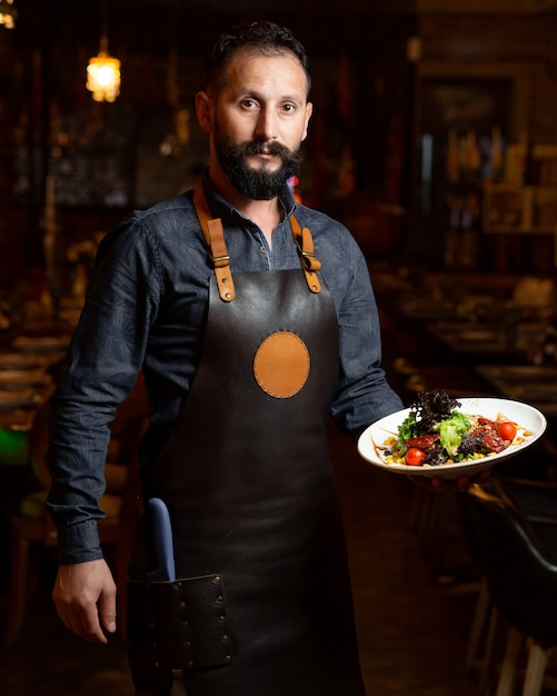 Foto gratuita camarero con plato de ensalada de verduras con lechuga de maíz nuez cereza y tomates secos