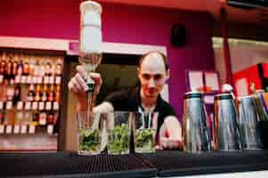 Foto gratuita camarero preparando cóctel mojito en el bar