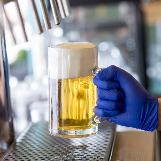 Camarero de primer plano con guantes y jarra de cerveza