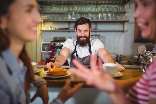 Foto gratuita camarero que sirve una taza de café y alimentos dulces a los clientes