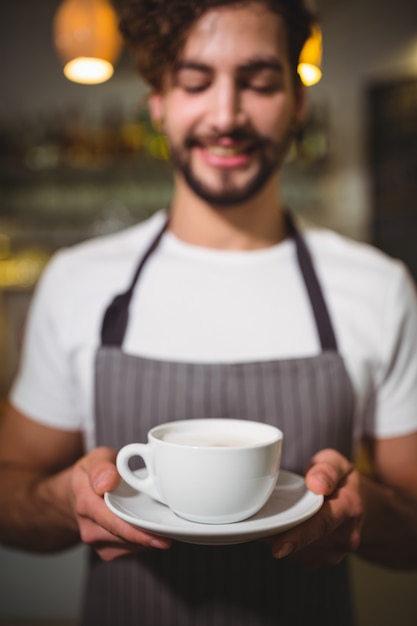 Camarero que sostiene una taza de café en la cafetería ©