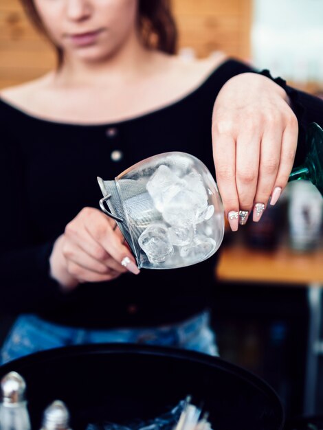 Camarero de sexo femenino que prepara la bebida con hielo