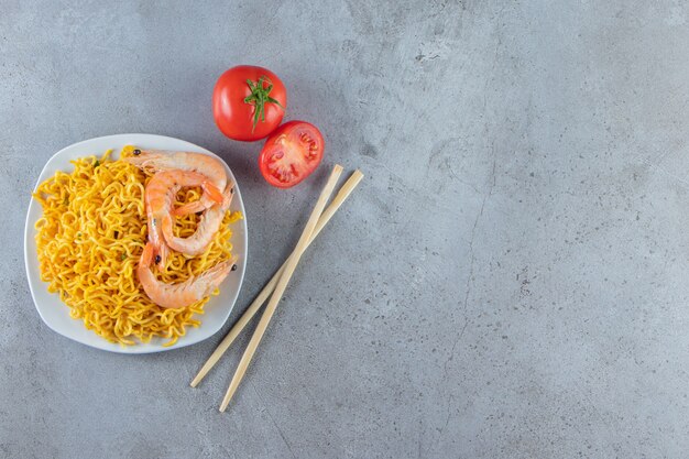 Camarones y fideos en un plato, sobre el fondo de mármol.