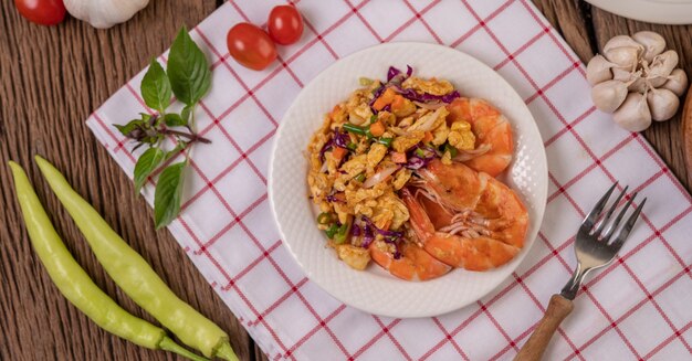 Camarones fritos con huevos en un plato blanco colocado sobre un paño con un tenedor.