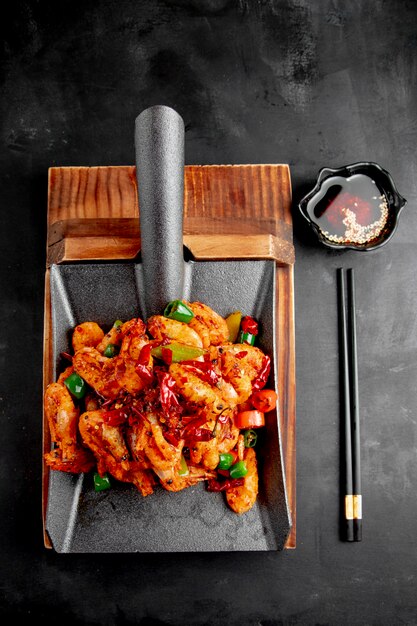 camarones fritos con pimientos rojos y verdes sobre una tabla para cortar madera