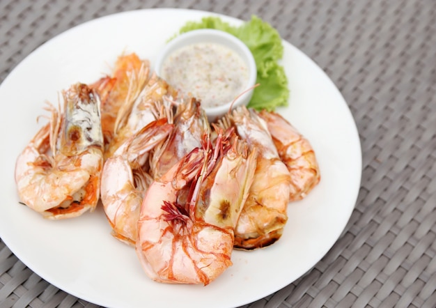 camarones a la parrilla con salsa de mariscos en plato blanco