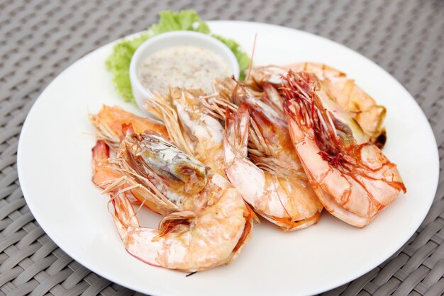 camarones a la parrilla con salsa de mariscos en plato blanco