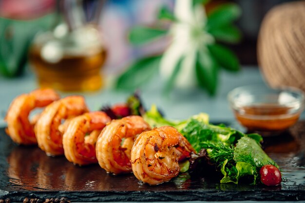 Camarones a la plancha con ensalada de hierbas frescas sobre tablero de piedra negra