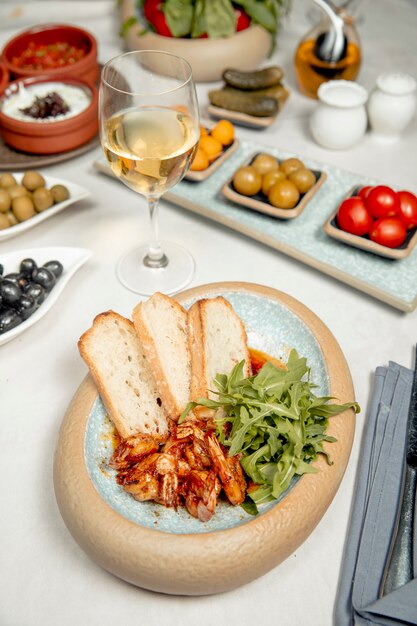 camarones con rúcula y pan servido con vino blanco