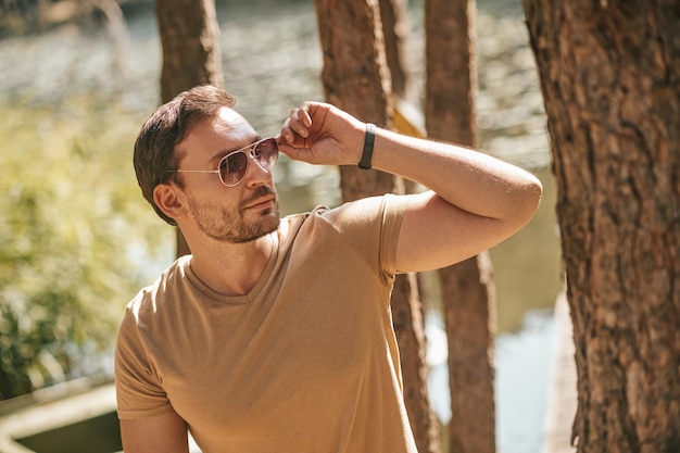 Camina en el bosque. Un joven con gafas de sol en el bosque cerca del río.