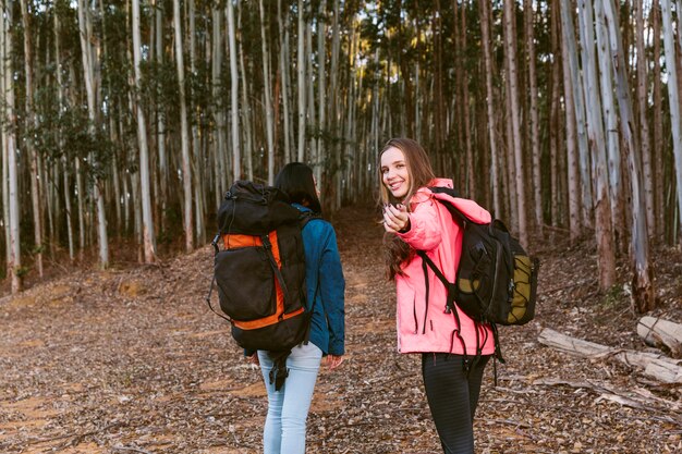 Caminante femenino que gesticula mientras que camina con su amigo en bosque