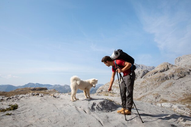 Caminante fundando un lindo perro blanco en las montañas