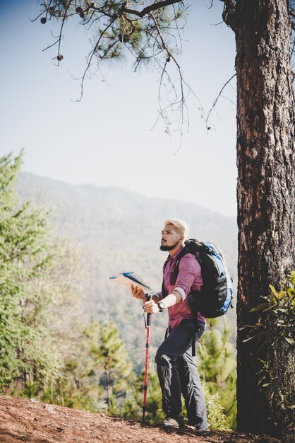 Caminante con mapa y gran mochila viajando viajando a la montaña.