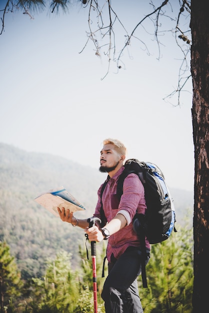 Caminante con mapa y gran mochila viajando viajando a la montaña.