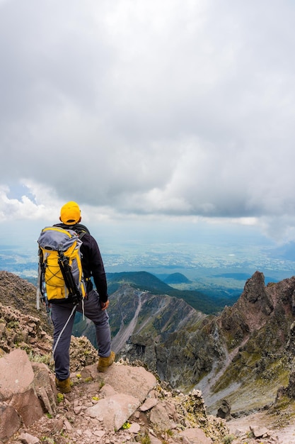 Caminante con una mochila de pie en la cima de la montaña