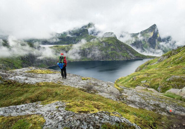 Caminante de pie junto a un lago en las montañas de Lofoten en un día brumoso