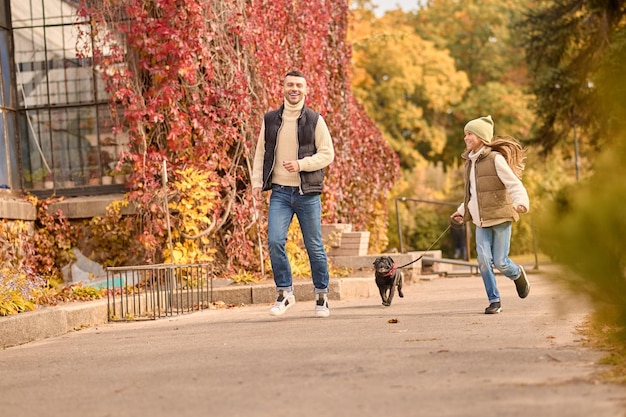 Caminata matutina. Un hombre y una niña corriendo con un perro.