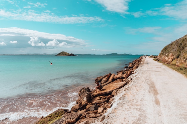 Foto gratuita camino cubierto de arena rodeado por el mar y las rocas bajo un cielo azul en río de janeiro.