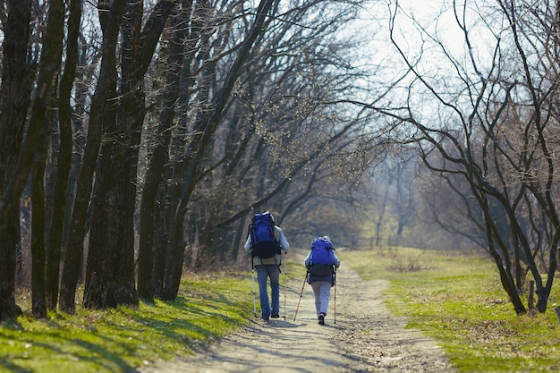 Camino de dos corazones amorosos. Pareja de familia de hombre y mujer en traje de turista caminando en el césped cerca de árboles en un día soleado. Concepto de turismo, estilo de vida saludable, relajación y convivencia.