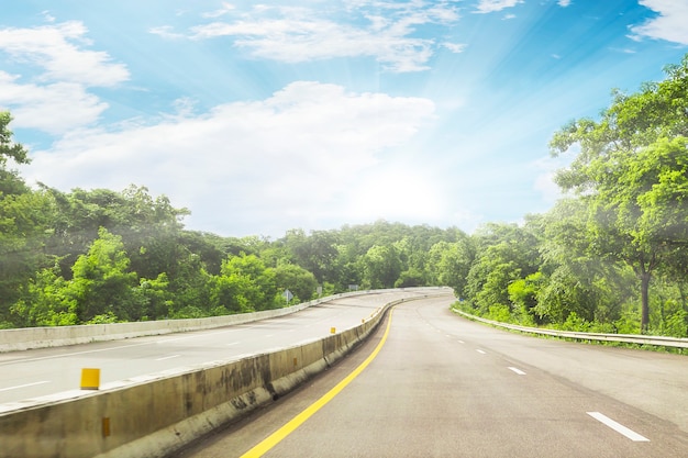 Camino hermoso de la carretera de Tailandia con el fondo verde de la montaña y del cielo azul